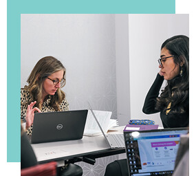 Two women working together at laptops