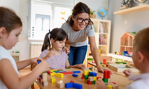 Teacher with glasses with kids at table