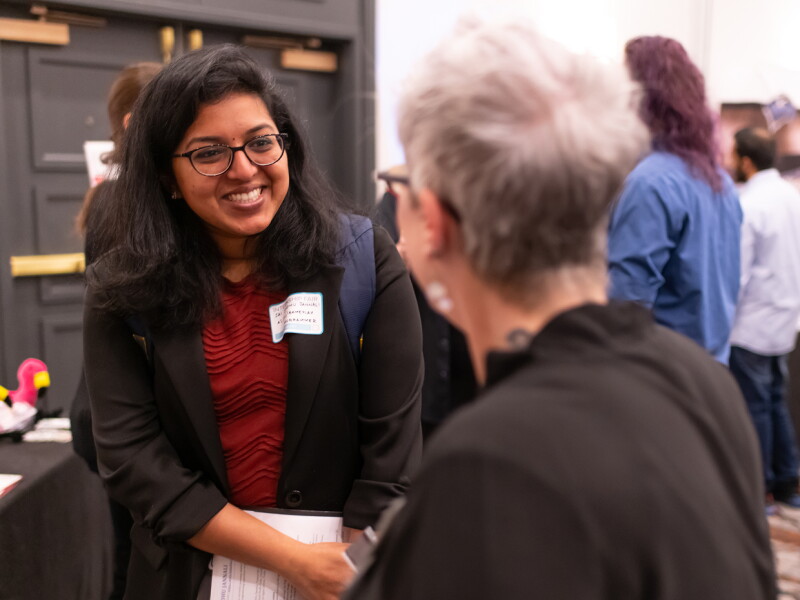 Student speaking with an attendee at a networking or career event.