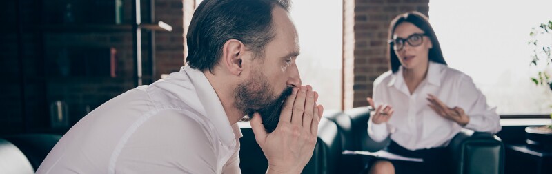 Man in a contemplative state during a counseling session, while the therapist engages in conversation