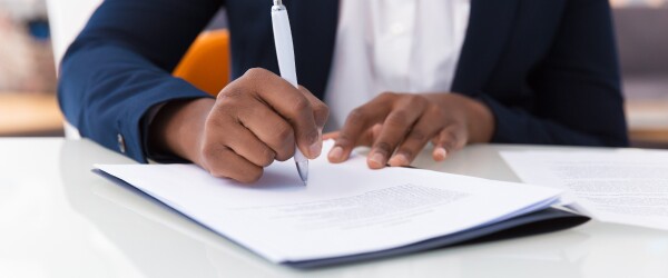 Professional in suit signs document on desk