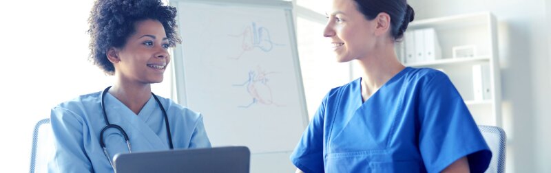 Female nurse with tablet discussing patient recommendations with nurse manager.