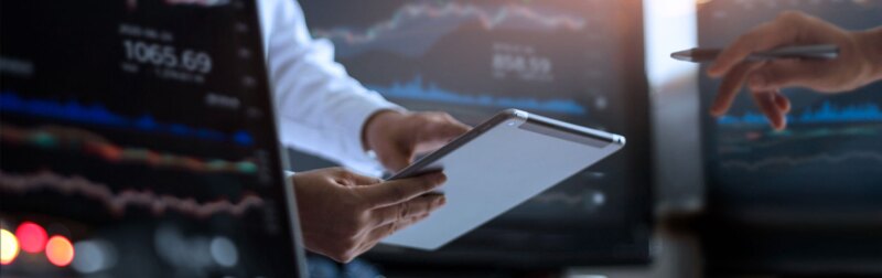 Businessman using tablet for analyzing data in monitoring room with team.