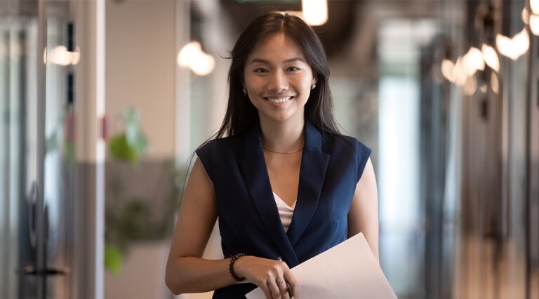 Smiling female professional in blue top holding papers