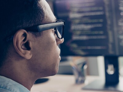 Rear view of a man worker on a computer with multiple monitors