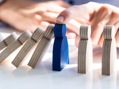 Businessperson stopping falling block on desk