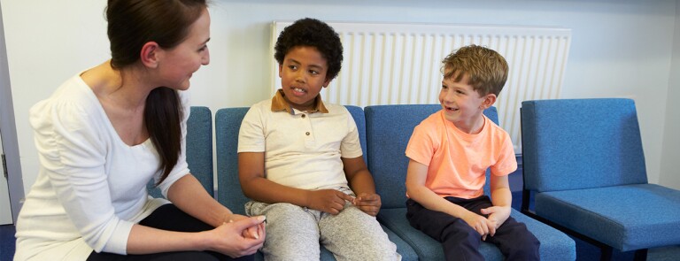 school counselor sitting down talking to two young boys
