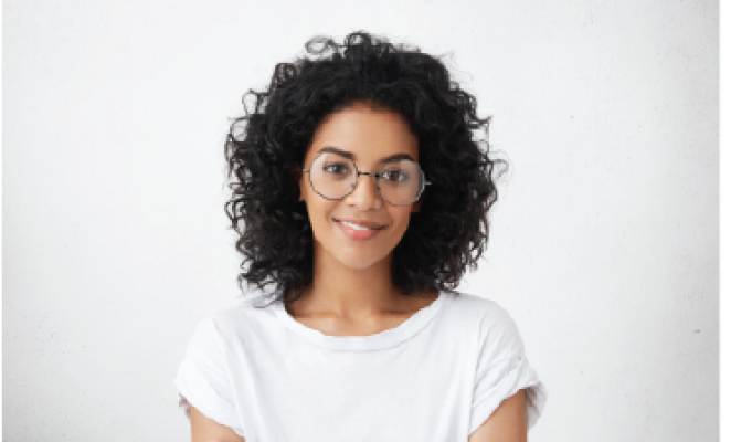 woman with curly black hair and glasses in white shirt