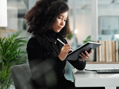 Health care compliance officer working on her tablet and laptop