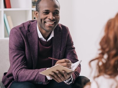 Smiling counselor takes notes while in session with a client