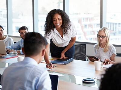 woman assisting students sitting around a table