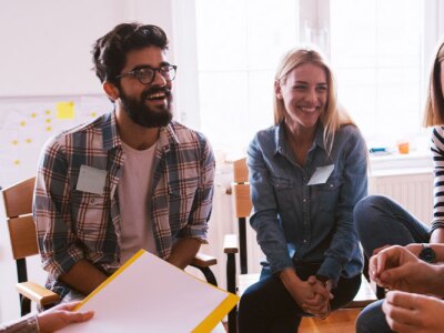 Female social worker sits with a group of volunteers to discuss ethical topics of social work.