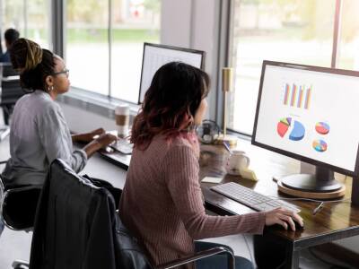 Women on desktop computers looking at graphs