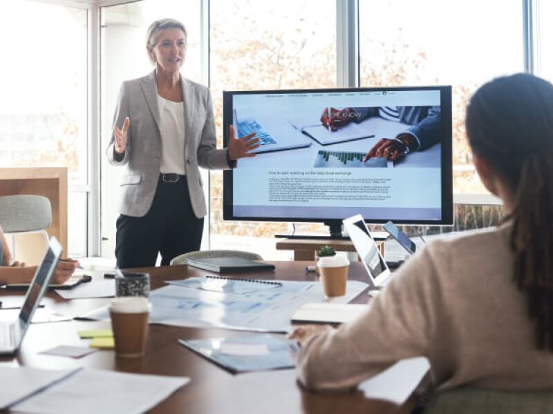 Woman leading presentation for colleagues in front of a large monitor