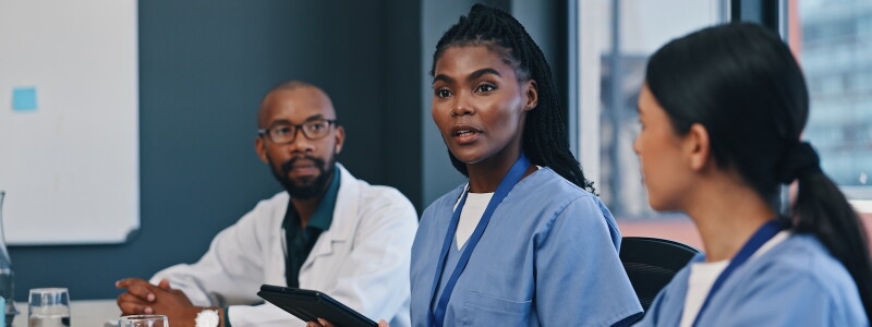 A nurse leads a meeting of attentive health care colleagues