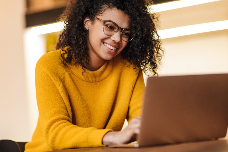 Woman in yellow sweater using laptop computer