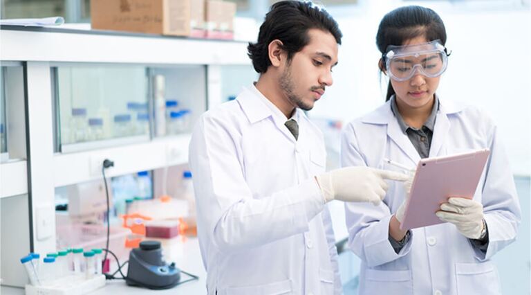 Male and female lab technicians looking at tablet