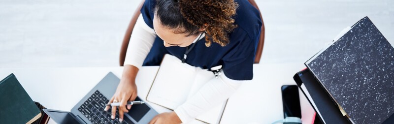 Overhead view of a nursing student studying at a desk with a laptop and books