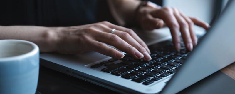 Close up of a woman's hands typing on a laptop