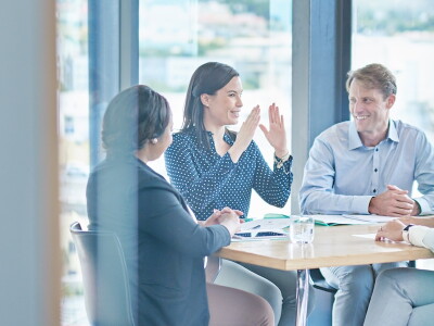 Colleagues enjoy a collaborative meeting around a table in front of large windows