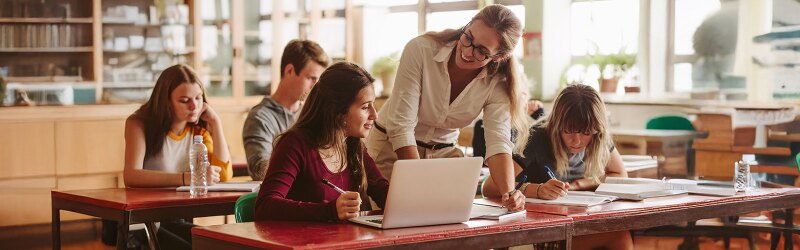 A teacher engaging with a student using a laptop