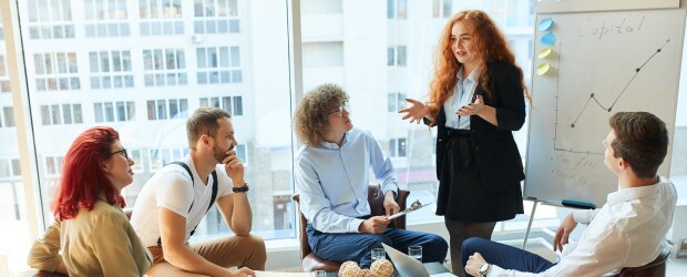 A group of young professionals sit together and discuss a chart
