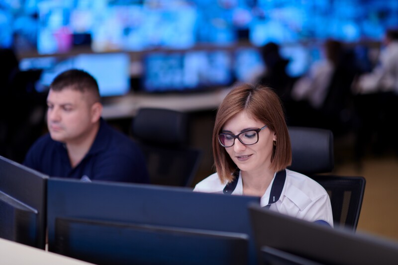 Female security operator working in a data system control room offices Technical Operator Working at workstation with multiple displays, security guard working on multiple monitors
