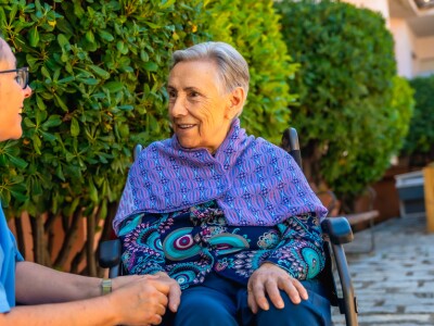 woman in wheelchair holding hands with nurse
