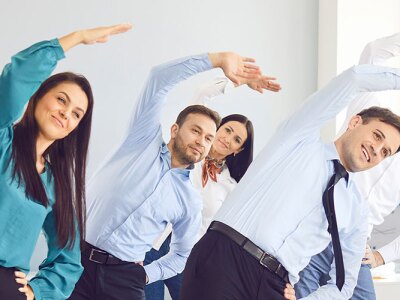 Office employees are participating in group stretching exercises as part of a workplace wellness program.