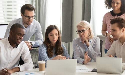 Group of Employees Gathered Around Laptop Screen