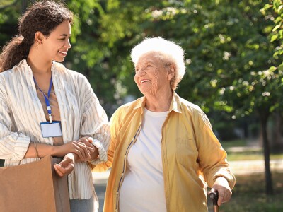 Young African-American female social worker walking with elderly woman outdoors
