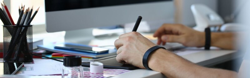 Male instructional designer arm holding graphic pad pen working on project.