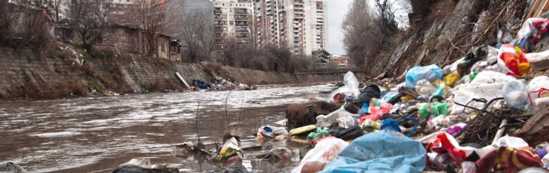 Landfill overflowing into river in an urban environment