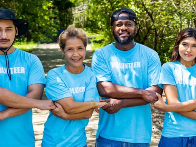 Volunteers holding hands in a chain facing the camera smiling