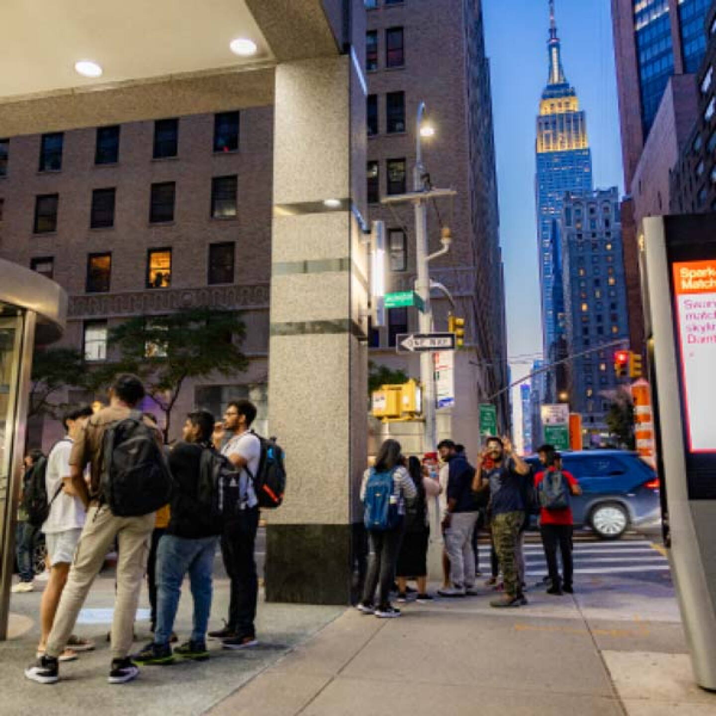 A group of Yeshiva University students gathers on a sidewalk in downtown New York City.