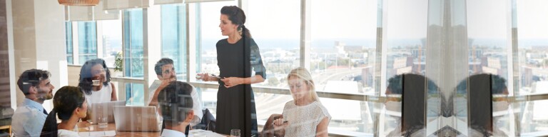 Woman leads a meeting standing up at the table in conference room