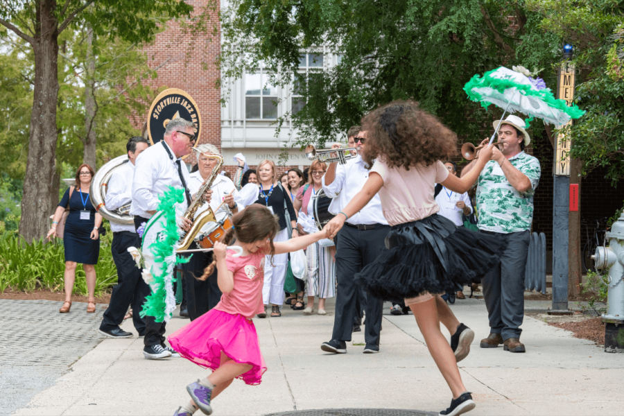 Two girls holding hands and dancing while jazz band plays