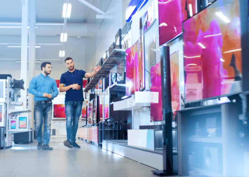 A retail salesperson shows a customer various television monitors