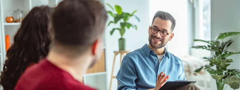A counselor listens to his clients with an encouraging smile