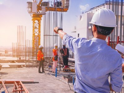 Smart civil architect engineer inspecting and working outdoors structure building site with blueprints.