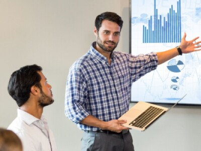 man in plaid shirt presenting pie chart to group