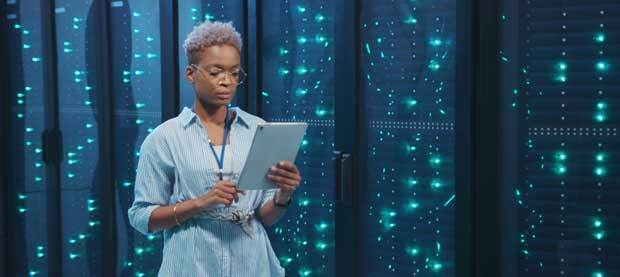 Tech professional in front of a bank of servers