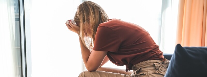 In a counselor's office, an exhausted woman sits with her head in her hands.