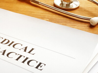 Document that reads "Medical Malpractice" rests on a desk next to a stethoscope and a gavel.