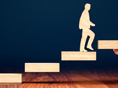 Woodblock illustration of a man walking up stairs while evaluating the career benefits of an online MBA versus an MEM degree.