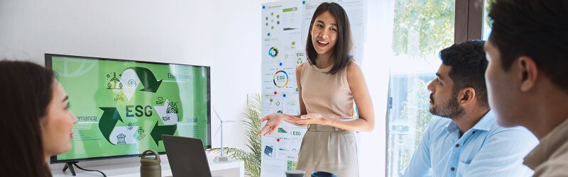 A woman presents a business ethics practice with ESG information to colleagues in a modern office setting.