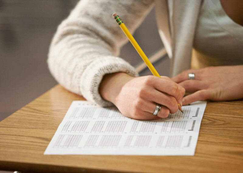 Hand with pencil filling in answers on standardized test sheet