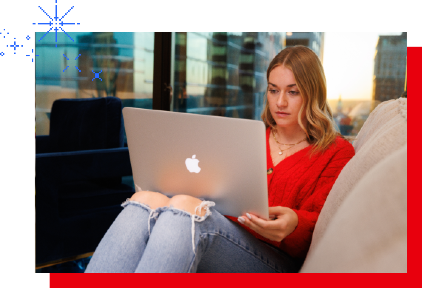 A female KU student sits on a couch while working on a laptop.