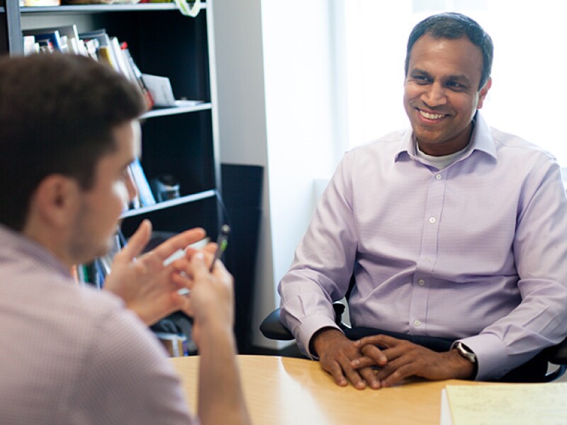 Two men smiling and speaking in an office