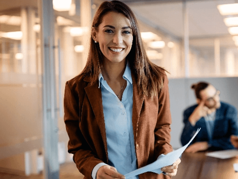 Woman smiling in front of colleagues at a conference table